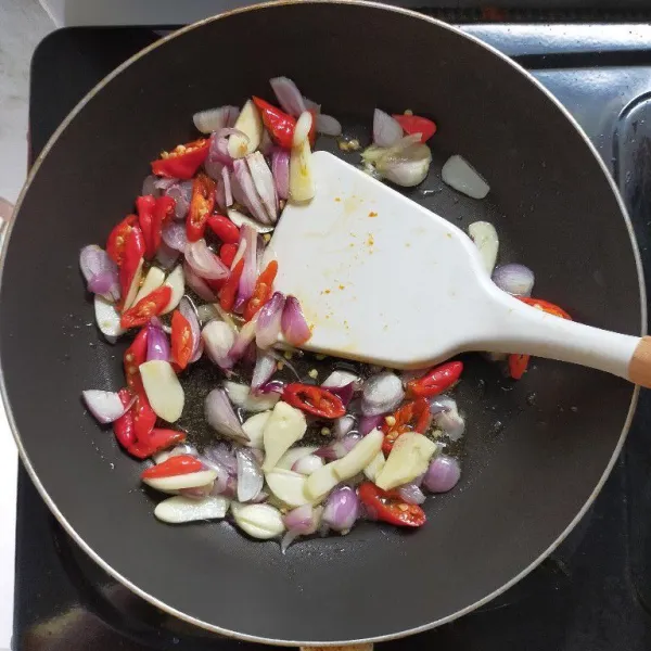 Tumis bawang merah, bawang putih, cabai merah keriting dan cabai rawit hingga layu.