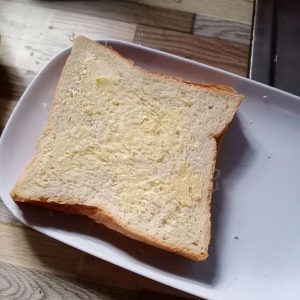 Tumpuk roti menjadi satu. Kemudian oles bagian atas dan bawah roti dengan margarin.