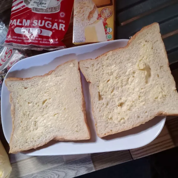 Oles permukaan roti dengan margarin.