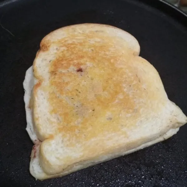 Tutup roti dengan roti tawar dan poles margarin bakar hingga matang kedua sisi, sajikan selagi hangat.