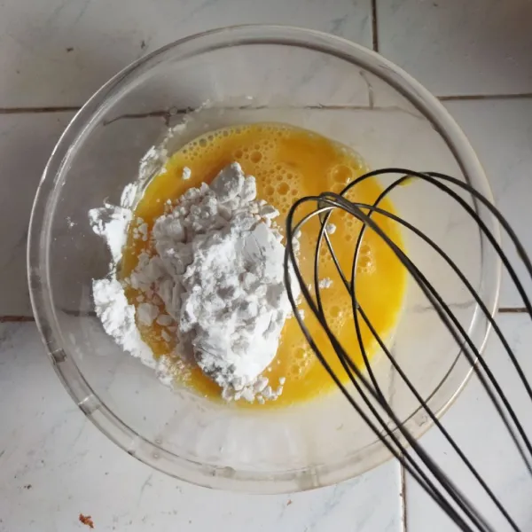 Pecahkan telur ke dalam wadah, tambahkan tepung tapioka dan aduk dengan whisk hingga tercampur rata.