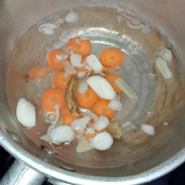 Rebus air hingga mendidih lalu masukkan bawang dan temu kunci terlebih dahulu. Setelah itu, masukkan wortel.