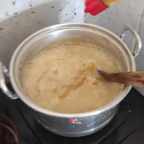 Bumbui bubur dengan garam, kaldu jamur, kecap asin dan minyak wijen masak aduk rata