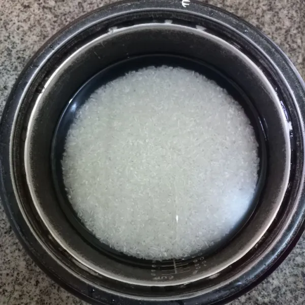 Cuci beras hingga bersih, tuang pada panci rice cooker, tambahkan air secukupnya.