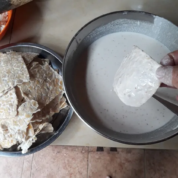 Celupkan tempe satu persatu ke dalam adonan tepung.