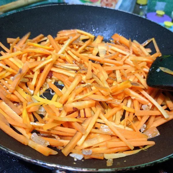 Masukkan potongan wortel, aduk merata. Masak hingga wortel setengah layu.