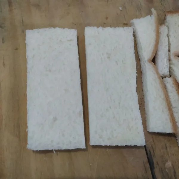 Buang pinggiran roti. Lalu potong roti menjadi dua.