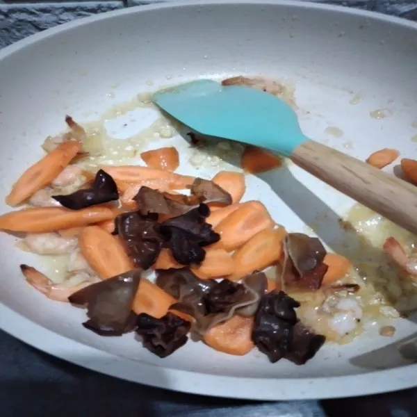 Tumis bawang putih dan jahe yang telah dihaluskan hingga harum, masukkan wortel dan jamur kuping, tumis hingga wortel lunak.