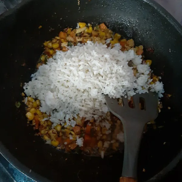 Aduk nasi hingga tercampur rata bersama bahan lainnya. Terakhir masukkan irisan daun bawang. Jika rasa sudah pas, nasi goreng siap disajikan.