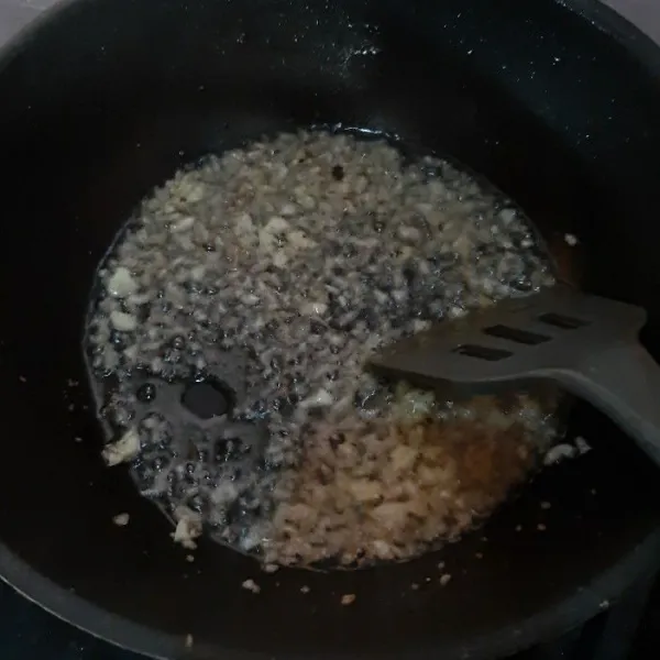 Panaskan minyak goreng di wajan, lalu tumis bawang putih dan bawang bombay hingga harum.
