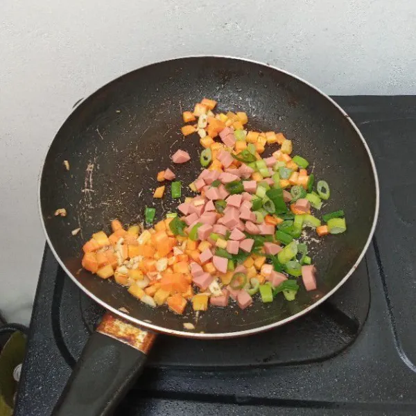 Masukkan secara bertahap wortel kemudian sosis dan daun bawang, masak hingga layu, sisihkan.
