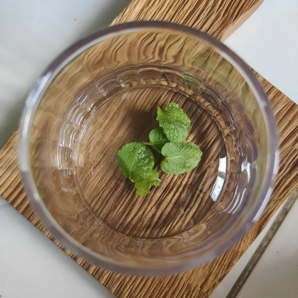 Cuci bersih dan remas-remas daun mint, masukkan ke dalam gelas