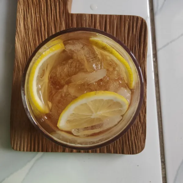Masukkan es batu dan irisan lemon ke dalam gelas