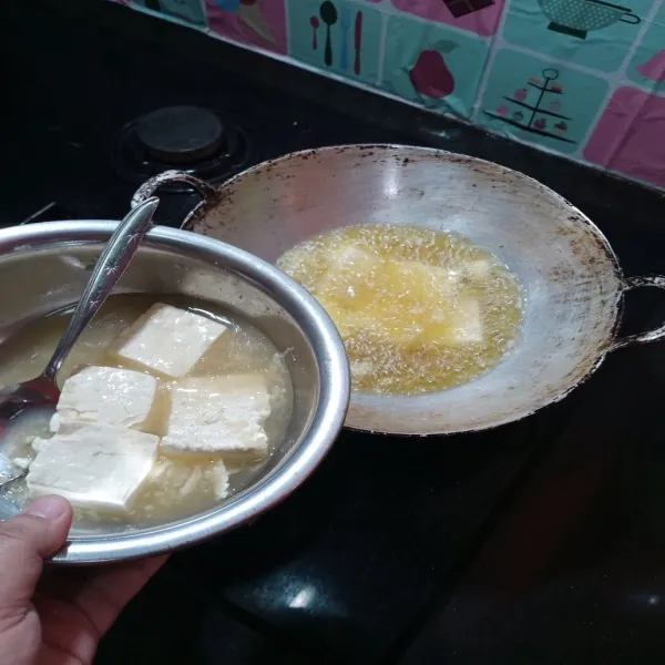 Panaskan minyak dalam wajan, lalu goreng tahu hingga kuning ke emasan.