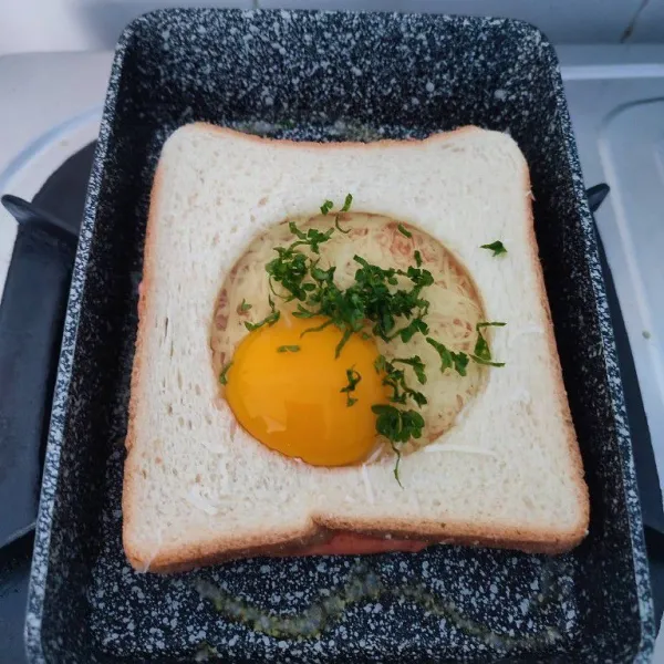 Panggang roti tawar dan tambahkan telur dan parsley cincang ke dalam lubang.