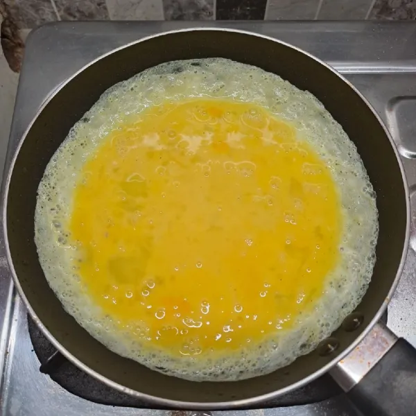 Panaskan teflon dengan sedikit minyak goreng, api kompor kecil saja. Tuang adonan telur, putar dan ratakan adonan telurnya.