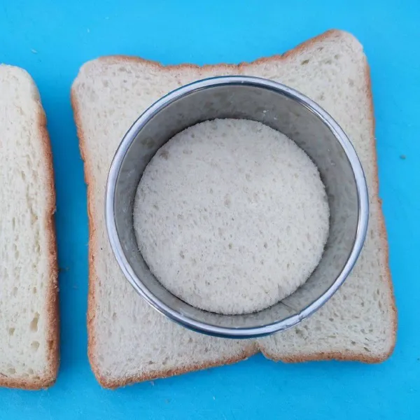 Siapkan roti tawar, kemudian buat lubang di salah satu roti.