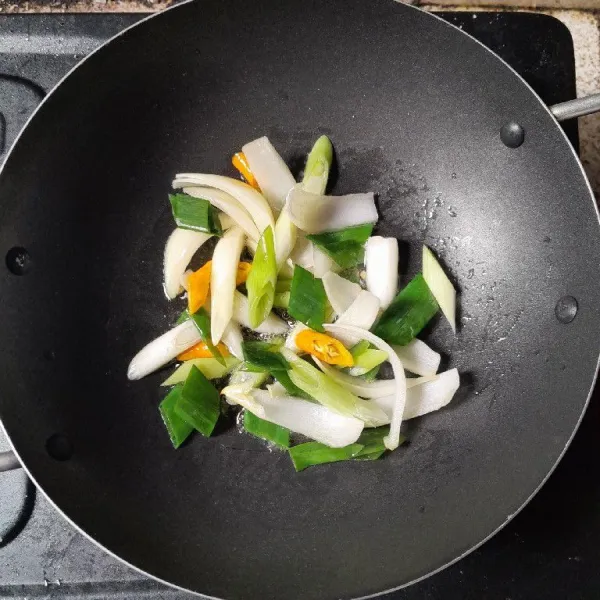 Tumis irisan bawang bombay, cabe rawit, dan daun bawang hingga matang dan harum.