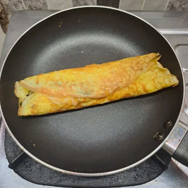 Gulung perlahan telur dadar. Masak sampai telur matang sempurna di dalam. Angkat dan iris telur gulung. Sajikan.