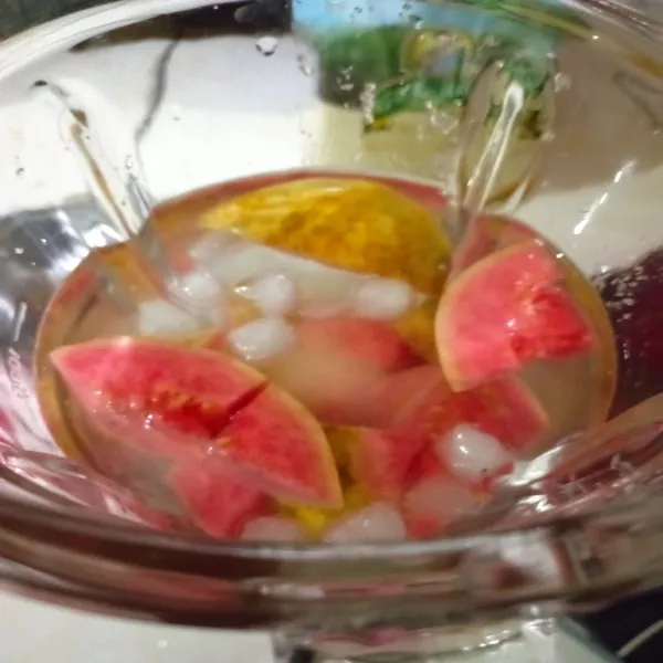 Masukkan jambu biji, gula pasir, air dingin dan es batu ke dalam gelas blender.