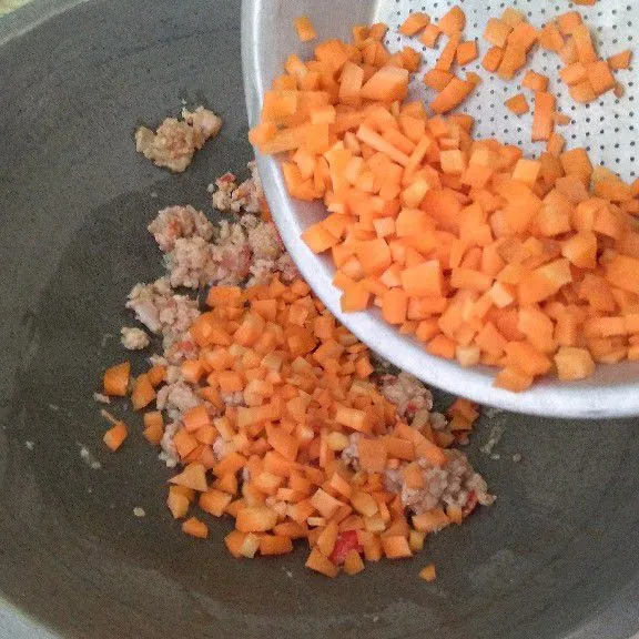 Masukkan daging ayam cincang, tumis hingga berubah warna lalu masukkan wortel dan air.
