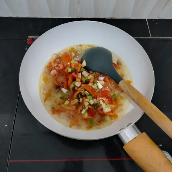 Kemudian masukkan tomat, daun bawang, kaldu bubuk dan garam. Aduk rata.
