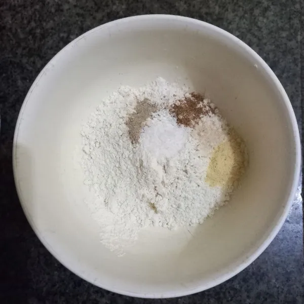 Dalam wadah campur terigu, tepung beras, garam, kaldu jamur, merica bubuk, ketumbar bubuk dan bawang putih bubuk, aduk rata.