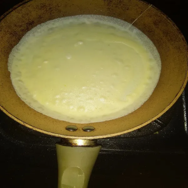 Panaskan teflon dengan api kecil, olesi margarin tipis-tipis (oles sekali saja, selanjutnya tidak perlu). Kemudian tuang 1 centong sayur adonan leker. Ratakan.