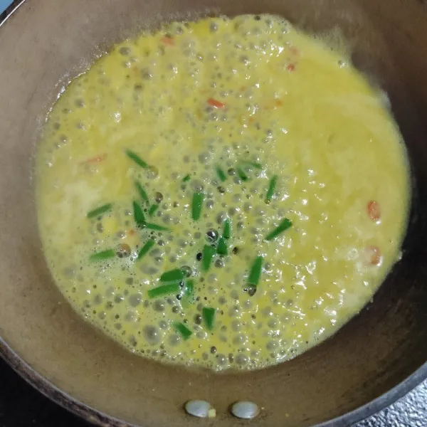 Masukkan kuning telur asin yang sudah dihaluskan dan dicampur dengan air, lalu tambahkan irisan daun bawang.