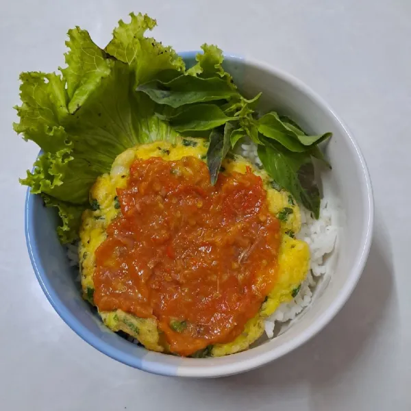 Ambil mangkok, beri nasi putih, daun selada, telur dadar, sambal dan daun kemangi. Sajikan.