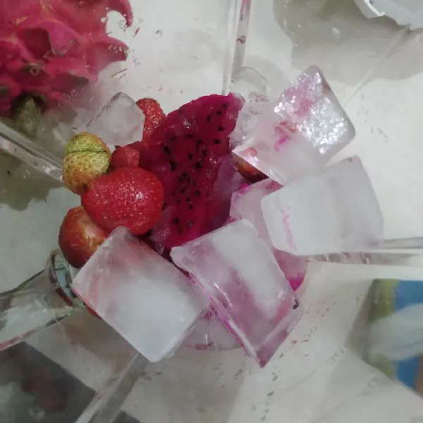 Masukkan potongan buah naga, strawberry, dan es batu ke dalam blender.
