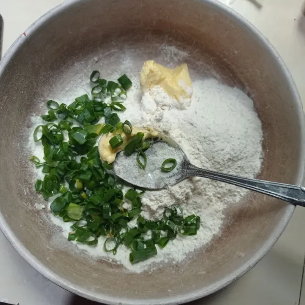 Masukkan tepung terigu, tepung bumbu, daun bawang, dan margarin ke dalam mangkok.
