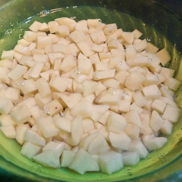 Kupas dan potong dadu kentang. Cuci bersih hingga air rendaman kentang bening.