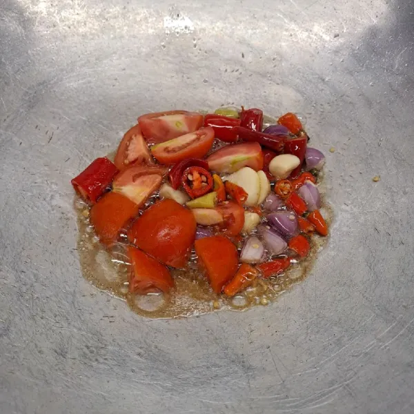 Goreng bawang merah, bawang putih, cabe merah, cabe rawit dan tomat sampai layu. Angkat dan pindah dalam cobek.