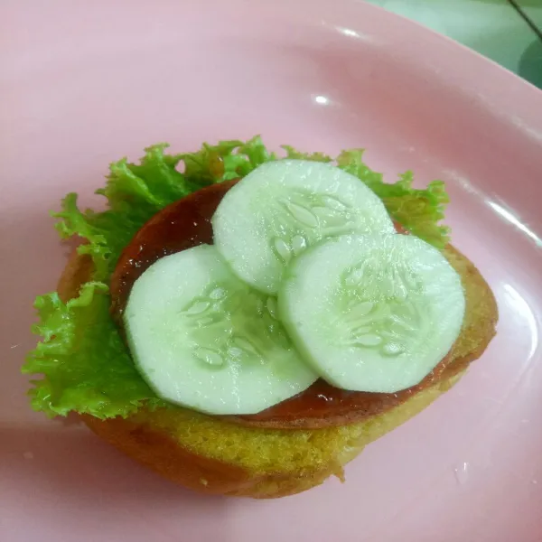 Ambil roti burger, susun selada, beef patty, saus sambal dan timun.