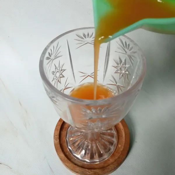 Tuang air jeruk ke dalam gelas.