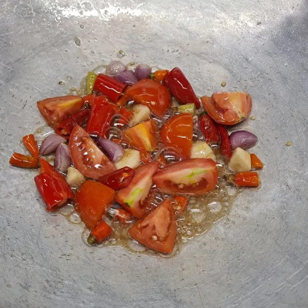 Potong kasar bawang merah, bawang putih, cabe merah, cabe rawit dan tomat. Kemudian goreng sampai layu. Angkat dan taruh di atas cobek.