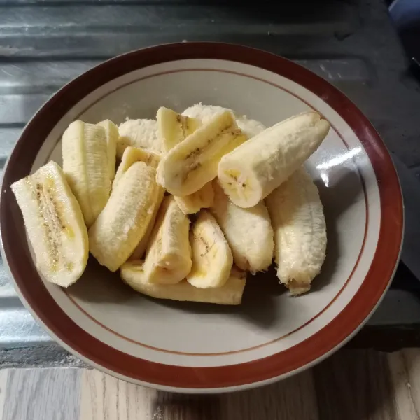 Kupas pisang kemudian potong menjadi 2 bagian. Tiap bagian belah menjadi 2 bagian.