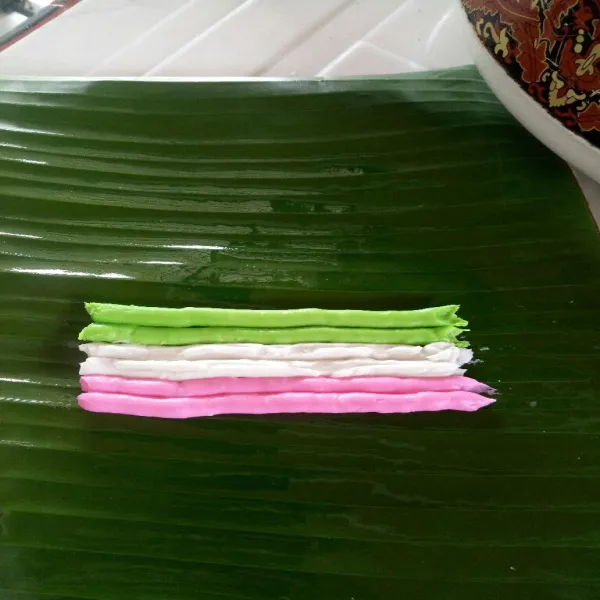 Alasi dengan daun pisang dan olesi minyak. Semprotkan sebaris dua baris perwarna di atas daun pisang.