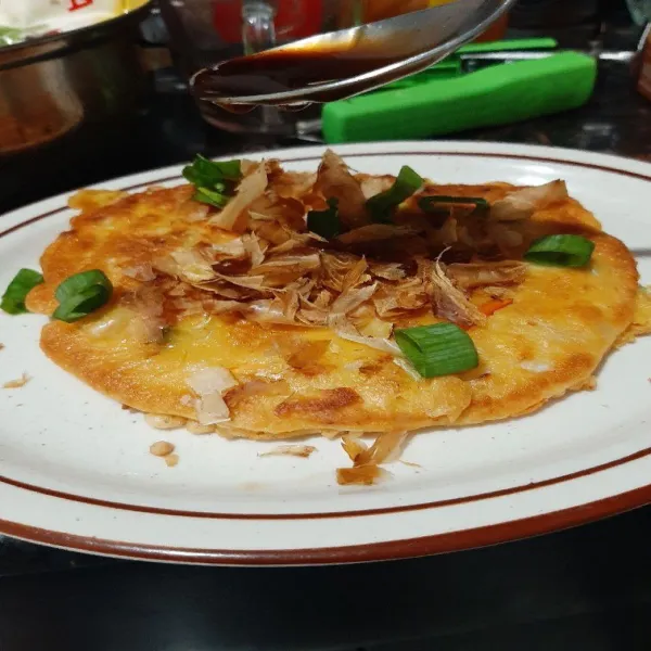 Tempatkan okonomiyaki dalam piring saji kemudian taburkan toping dan siram sauce. Tambahkan mayonaise jika di inginkan. Siap sajikan.