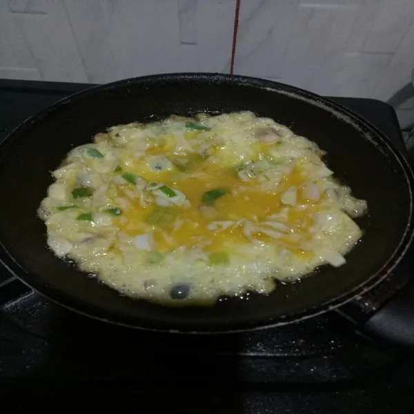 Panaskan minyak di teflon lalu masak telur hingga sisi bawah matang.