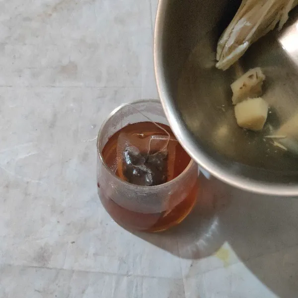 Siapkan gelas saji yang sudah berisi teh celup. Kemudian tuang air rebusan jahe.