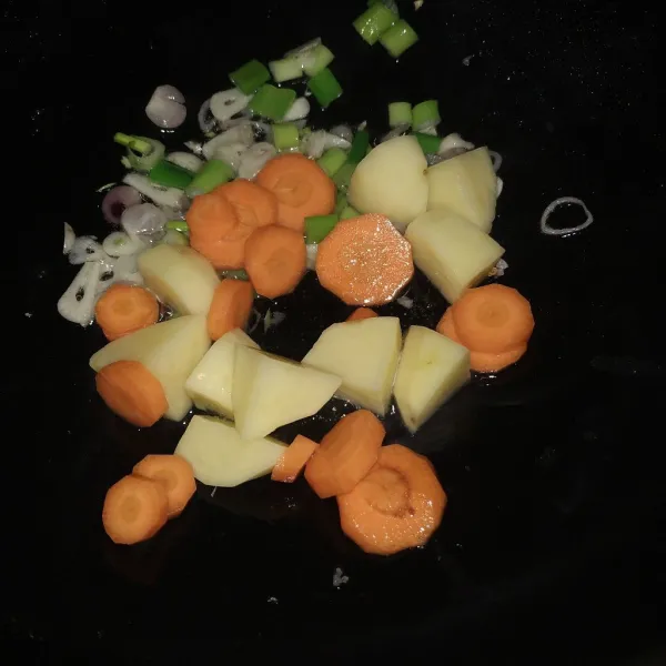 Tumis bawang hingga harum, tambahkan daun bawang, kentang dan wortel, tumis sebentar hingga berubah warna.
