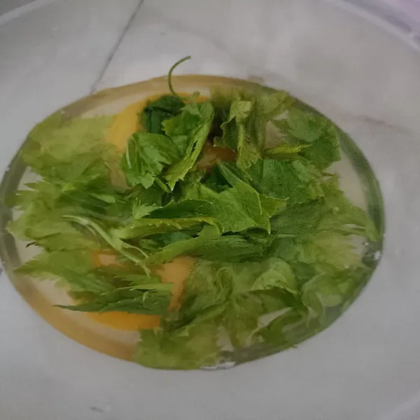 Ambil telur, pecahkan ke dalam wadah. Tambahkan daun seledri.