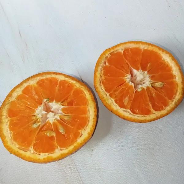 Potong melintang buah jeruk, lalu peras dan ambil airnya.