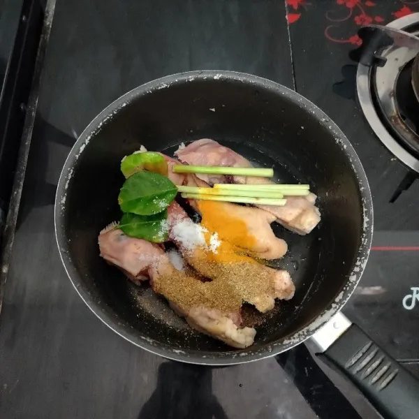 Setelah itu masukkan kepala ayam ke dalam panci. Tambahkan serai, daun jeruk, kunyit bubuk, ketumbar bubuk dan garam.