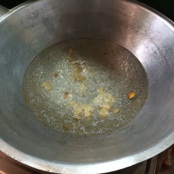 Panaskan minyak. Lalu tumis bawang putih sampai harum dan tambahkan air.