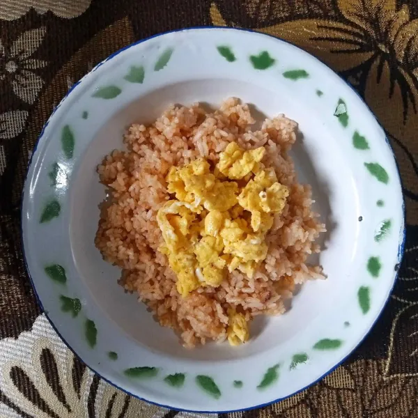 Sajikan nasi goreng dengan telur orak-arik.