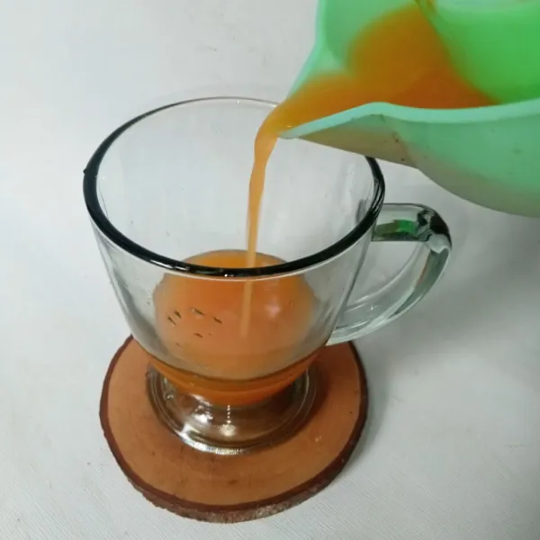 Tuang air jeruk ke dalam gelas.