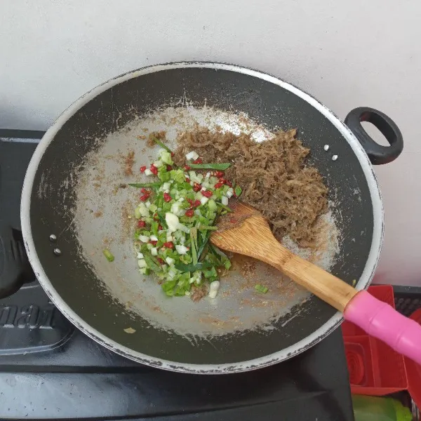 Setelah matang kepinggirkan ikan dan masukkan bawang putih, cabe dan daun bawang, masak hingga layu.